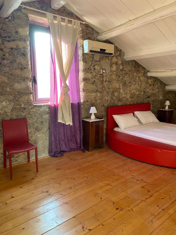 Marano MarchesatoIl Casale的一间卧室配有红色的床和椅子