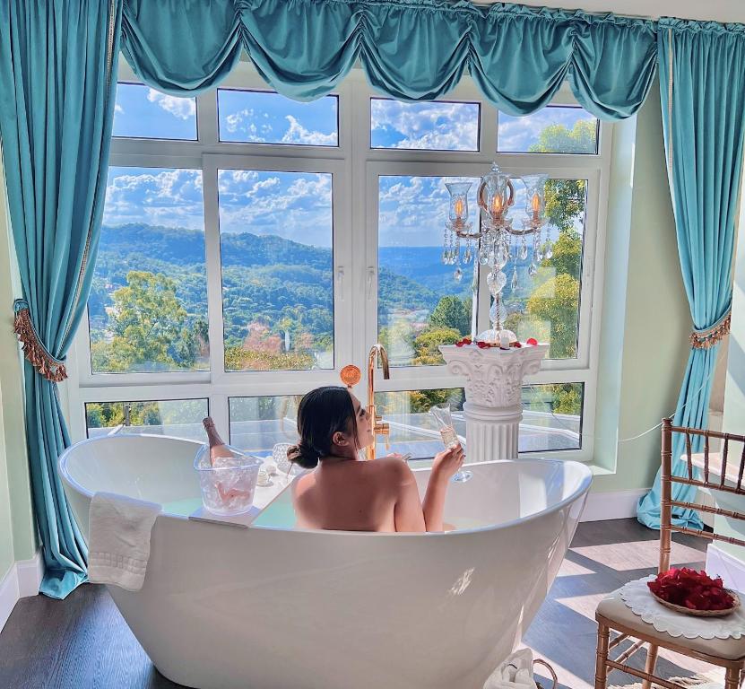 格拉玛多Le Boutique Hotel Gramado - Exclusivo para Casais的坐在窗前浴缸中的女人
