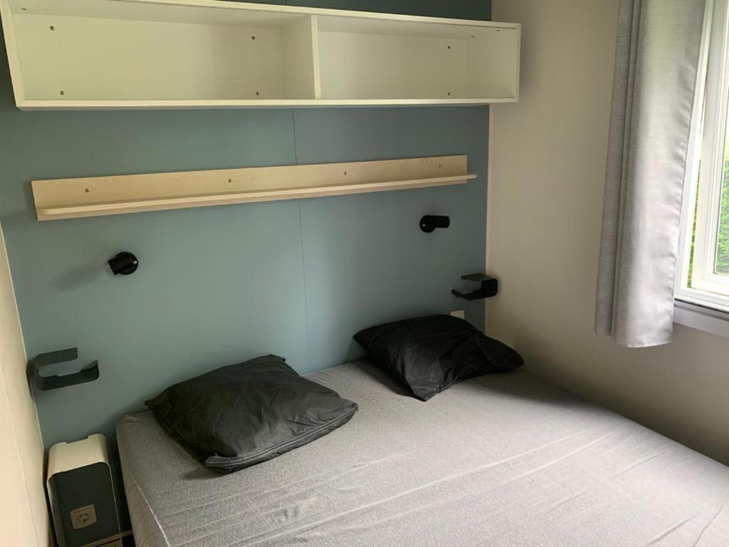 乌伊斯特勒昂Mobil-home Ouistreham的小房间设有一张带两个枕头的床