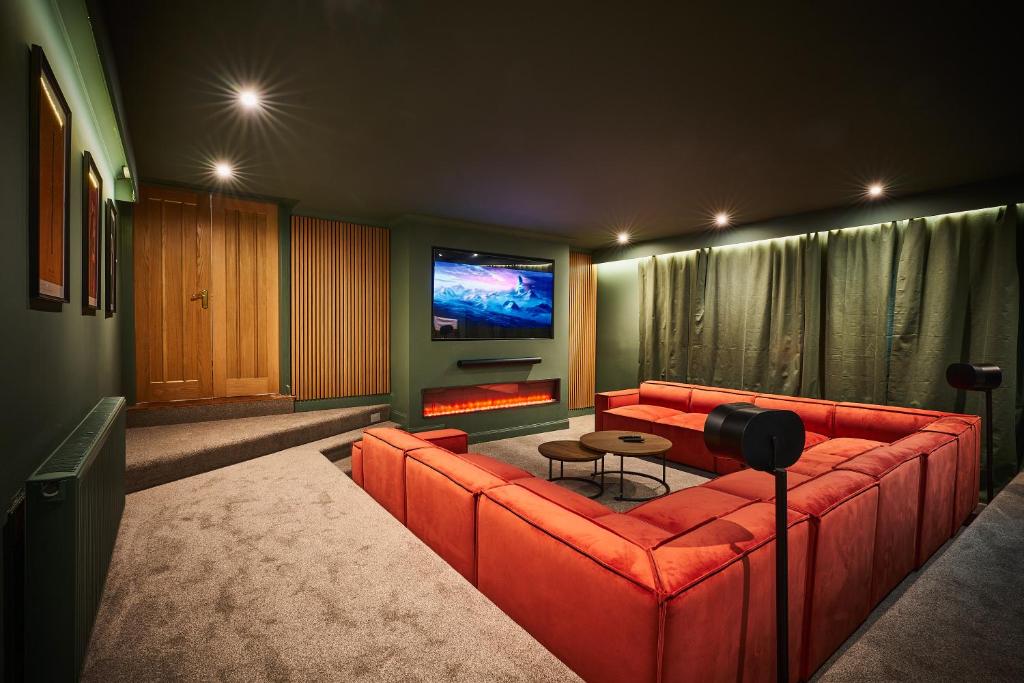 阿利士The Old Stables - Hot Tub, Sauna and Cinema的客厅配有红色沙发和平面电视