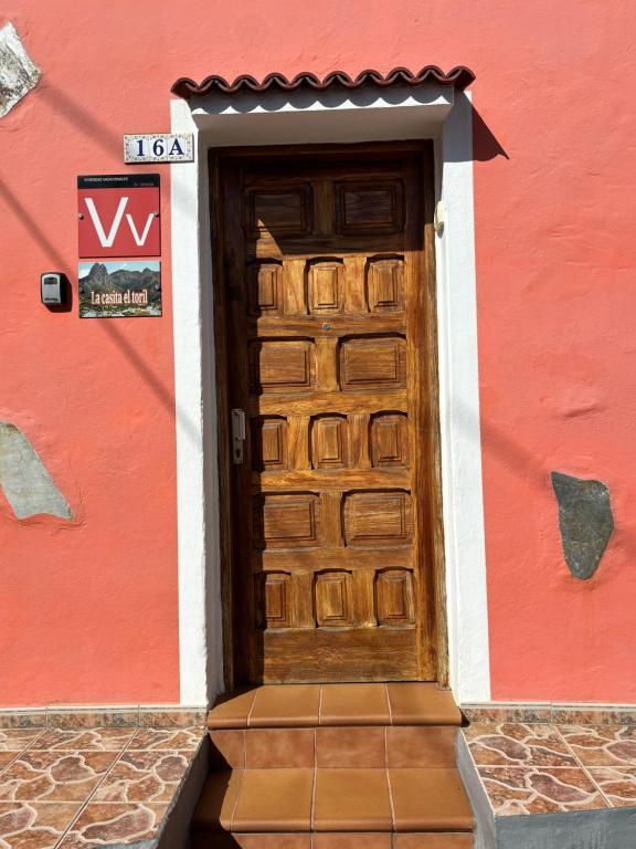 巴尔塞基略Chalet Rutas de Valsequillo的红色建筑上带有标志的木门