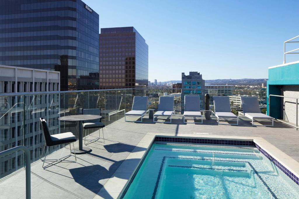 洛杉矶AC Hotel by Marriott Beverly Hills的大楼内带桌椅的屋顶游泳池
