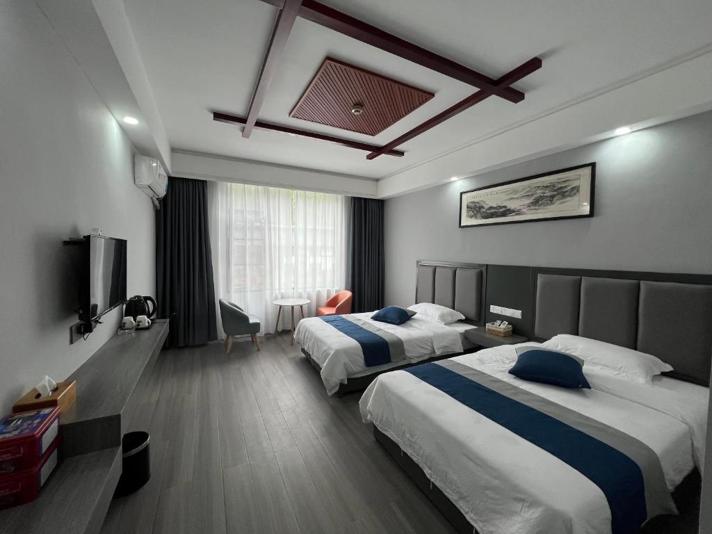 张家界Zhangjiajie Happy Inn的酒店客房设有两张床和电视。