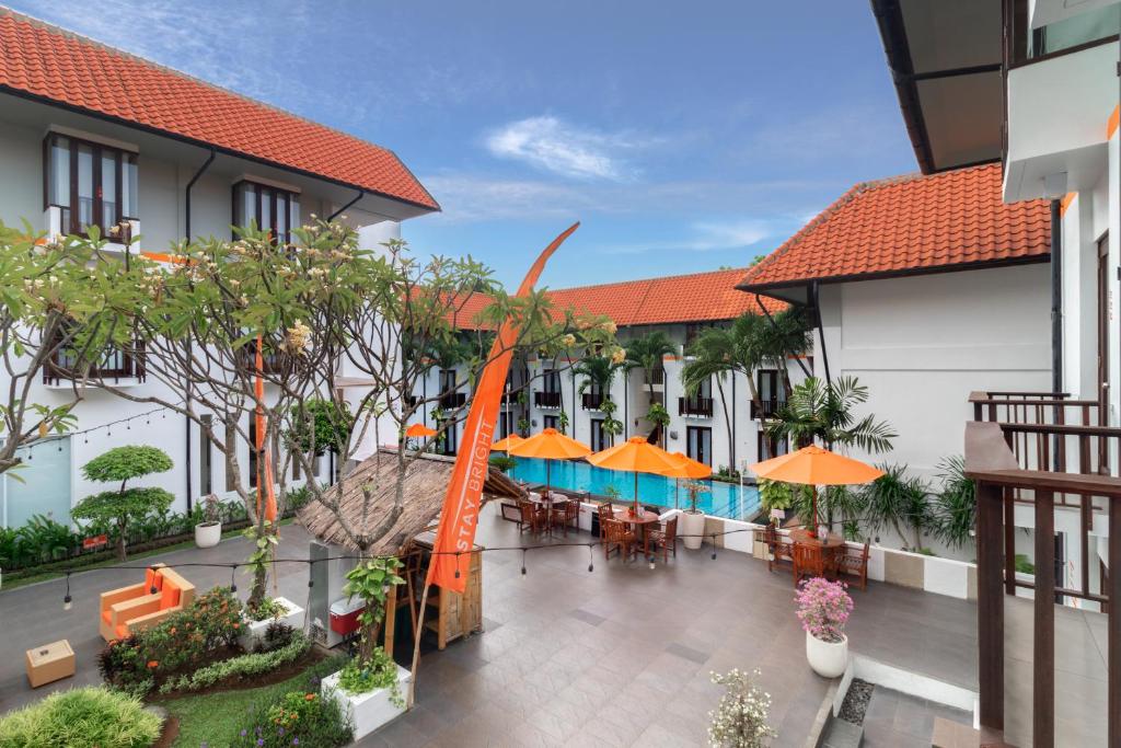 库塔HARRIS Hotel Kuta Tuban Bali的室外庭院配有桌椅和遮阳伞。