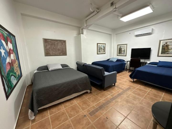 马亚圭斯Newly remodeled 3 BR Center Mayagüez, First Floor Unit1的客房设有两张床、一张沙发和一台电视。