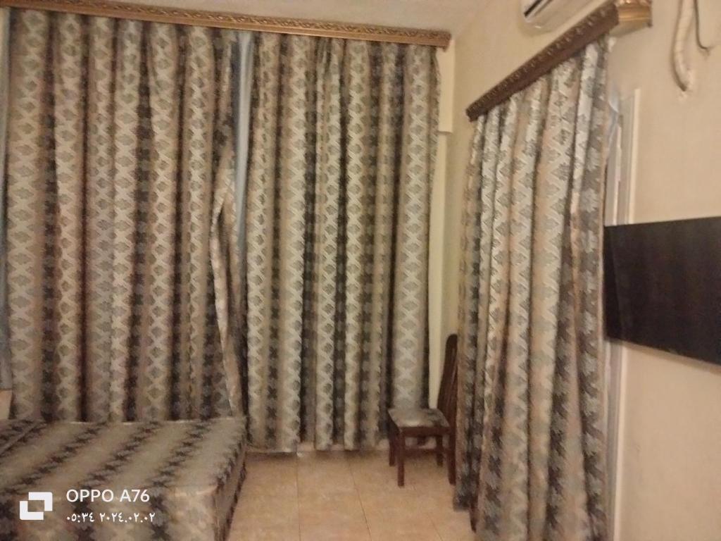 开罗Anubis Hostel的一间卧室配有床、电视和窗帘