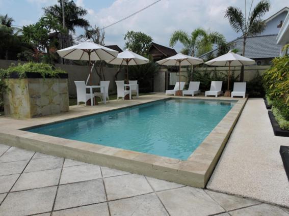 罗威那卡迪卡别墅酒店的一个带白色椅子和遮阳伞的游泳池