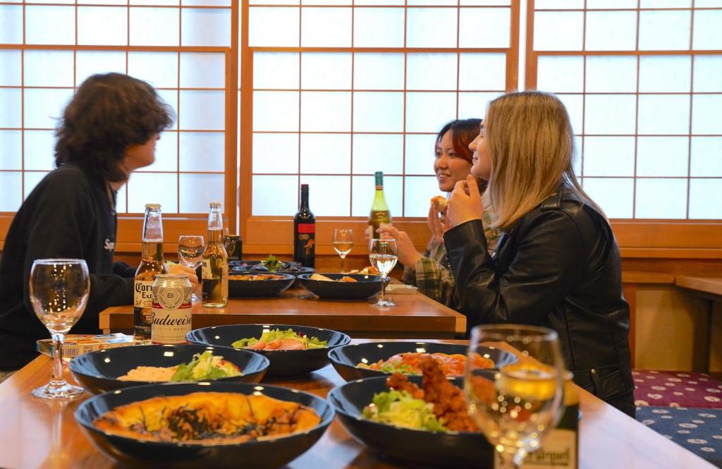 东京COGO Ryogoku的一群坐在餐桌旁吃着食物的妇女