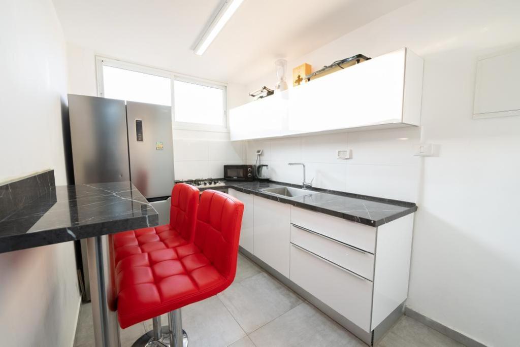 巴特亚姆Beautiful apartment near Tel Aviv的白色厨房里配有红色椅子的厨房