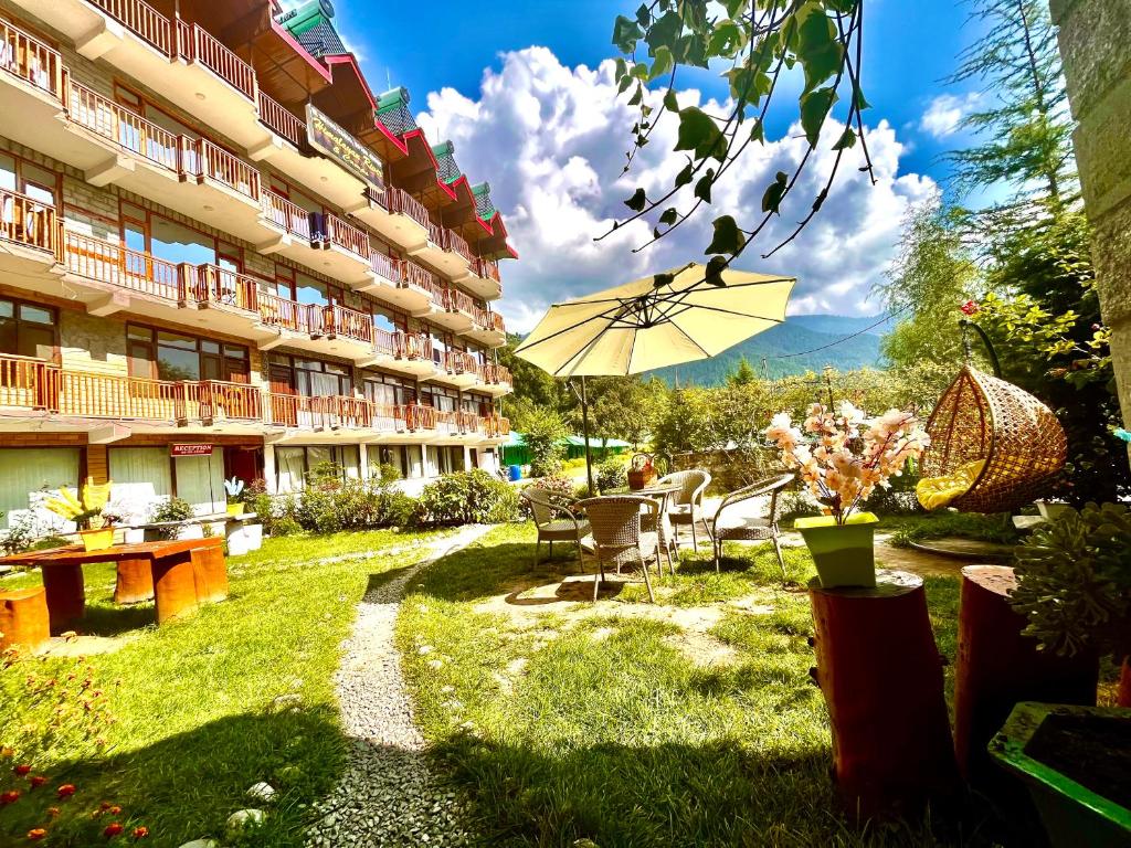 马拉里Himalayan Riverside Resort, Manali的酒店庭院配有桌子和遮阳伞
