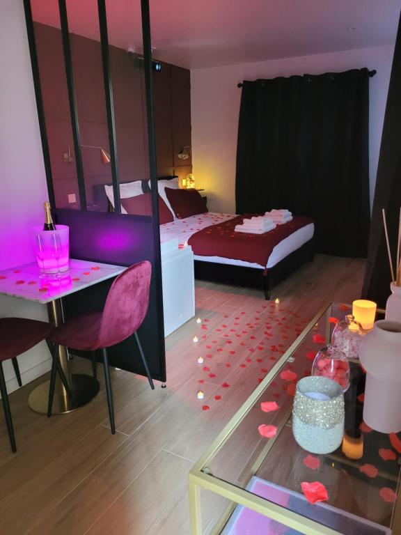 土伦Nuit d'évasion love room avec baignoire balnéothérapie的卧室配有一张床和一张桌子,地板上摆放着心花