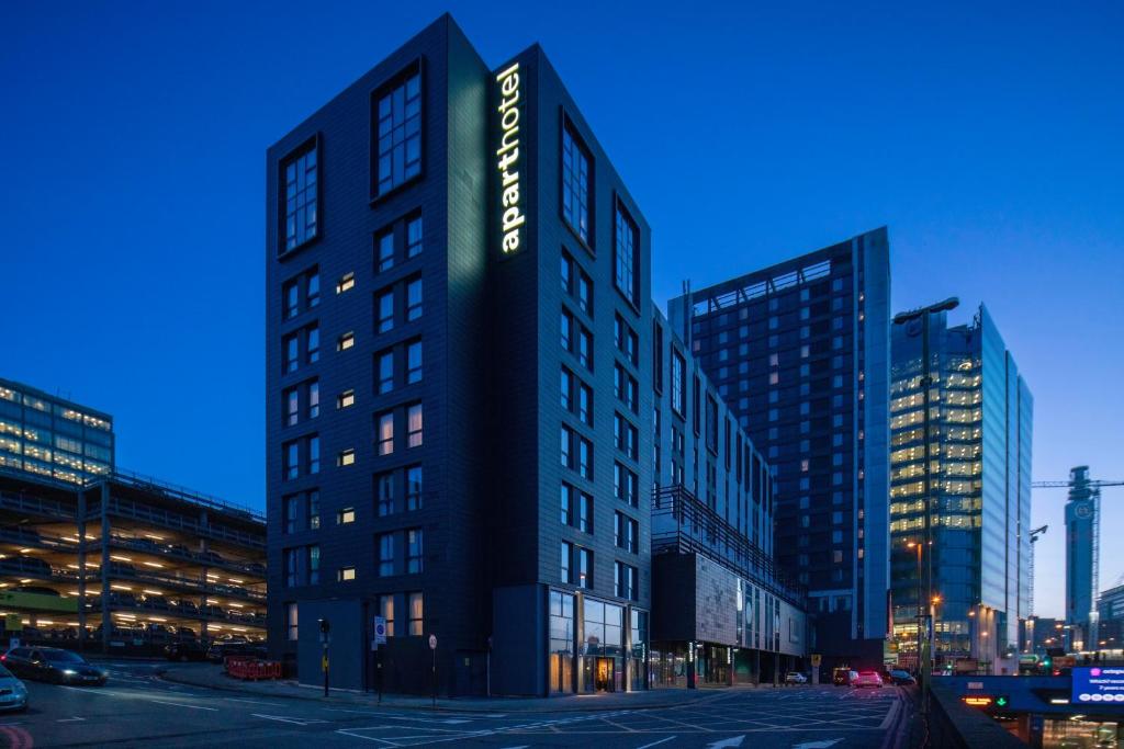 伯明翰Aparthotel Birmingham的一座高大的建筑,旁边有一个标志