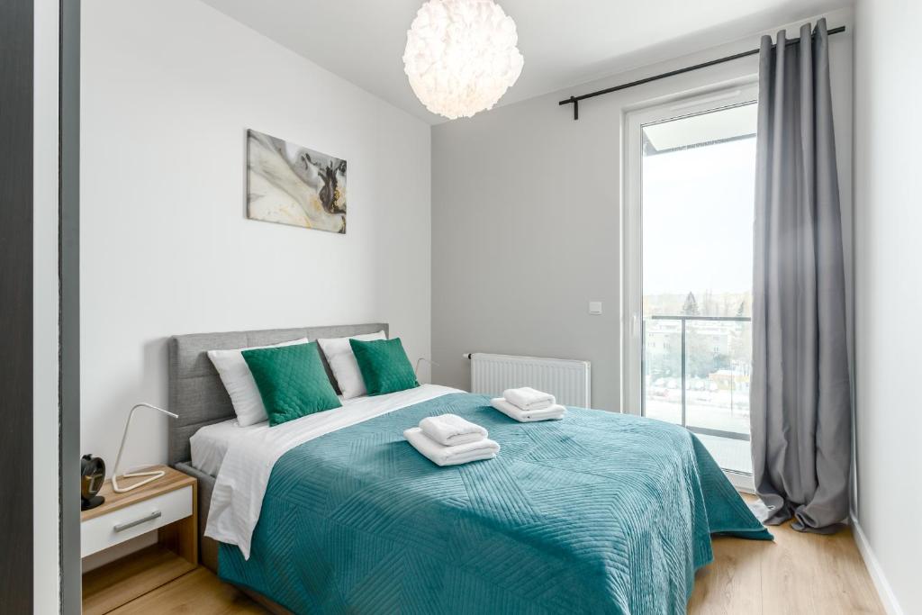 华沙Warsaw City River View的一间卧室配有一张带蓝色毯子的床和窗户。