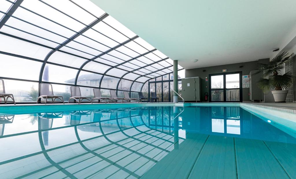滨海迪沃Kyriad Prestige Residence & Spa Cabourg-Dives-sur-Mer的一个带玻璃天花板的室内游泳池