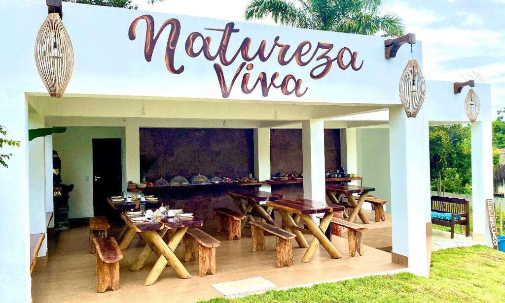 伊塔卡雷Pousada Natureza Viva的餐厅设有木桌和阅读自然藤的标志