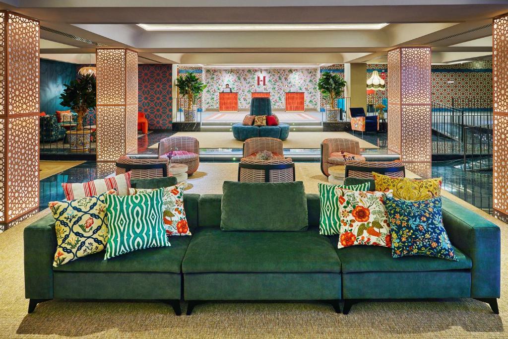 塞维利亚塞维利亚赫斯珀里亚酒店的大堂内带色彩缤纷枕头的绿色沙发