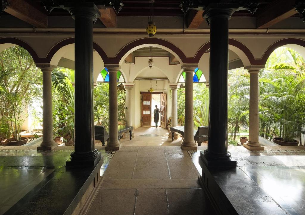 KānādukāttānSaratha Vilas Chettinad的一座有柱子的建筑和一条有树木的走廊