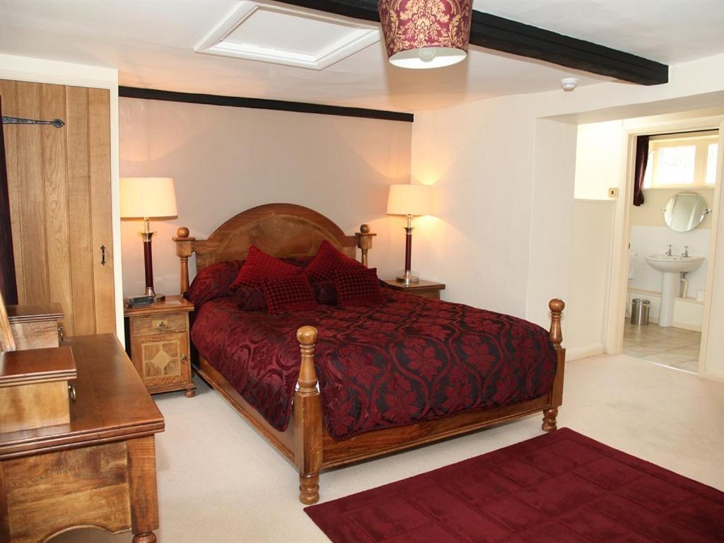 CollywestonThe Collyweston Slater的一间卧室配有一张大床和红色的床罩