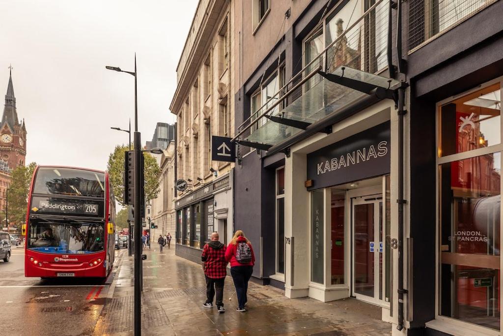 伦敦Kabannas London St Pancras的两个人乘坐公共汽车沿着城市街道走