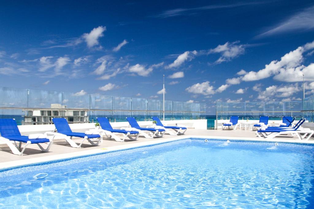 圣安德烈斯Azure Lofts & Pool的一座带蓝色椅子的建筑屋顶上的游泳池
