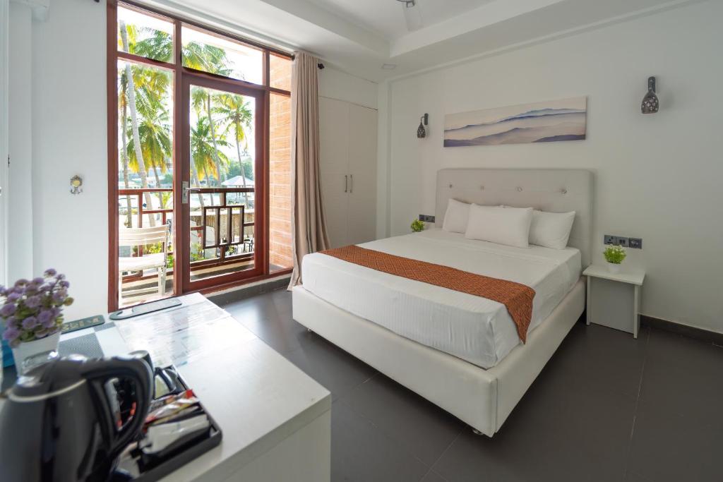 呼拉Silver Oasis Maldives的白色的卧室设有床和大窗户