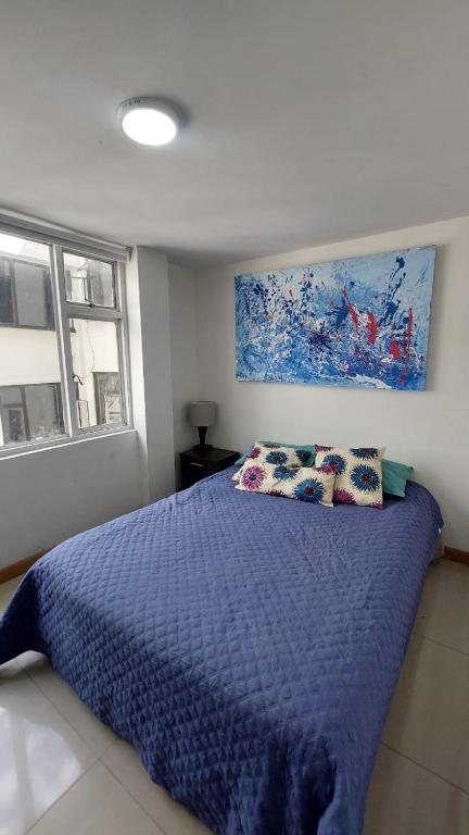 波哥大APARTAMENTO CHAPINERO CENTRAL的一间卧室配有蓝色的床、枕头和绘画