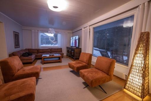 塞伊奈约基Villa Närhi 230 m2 upea talo rauhallisella alueella的客厅配有沙发、椅子和电视