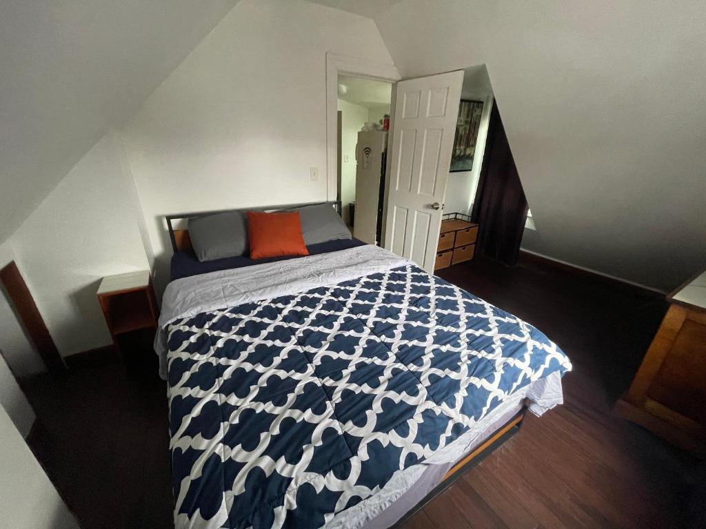 East ElmhurstPrivate Loft 5 min away from LGA的卧室配有蓝色和白色的床和橙色枕头