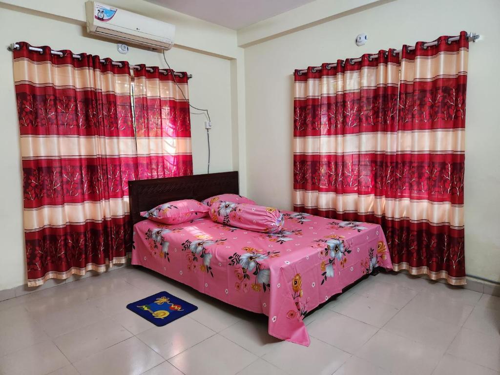 达卡Aaira guest house的一间卧室配有粉红色的床和红色窗帘