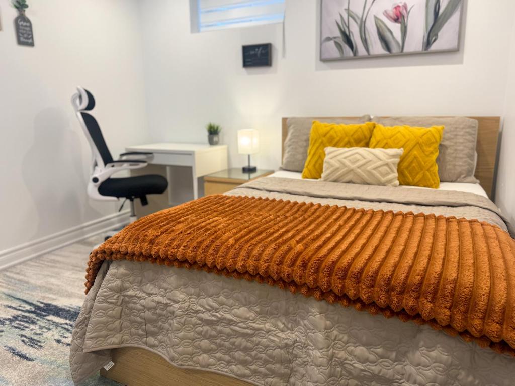 惠特比Whitby Private Rooms的一间卧室配有一张带橙色毯子的床和一张书桌