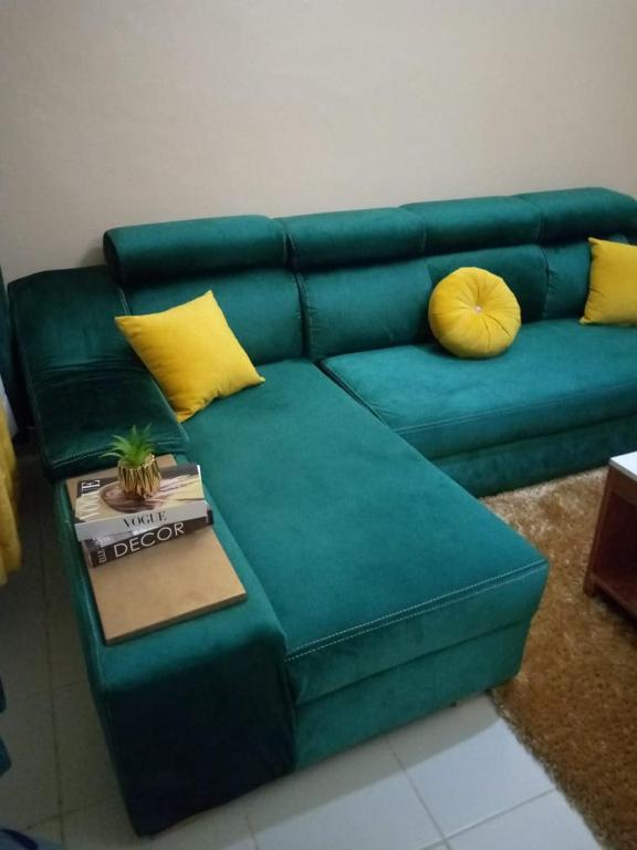 EmbuEmbu Paradise 1 bedroom AirBNB的绿色沙发、黄色枕头和桌子