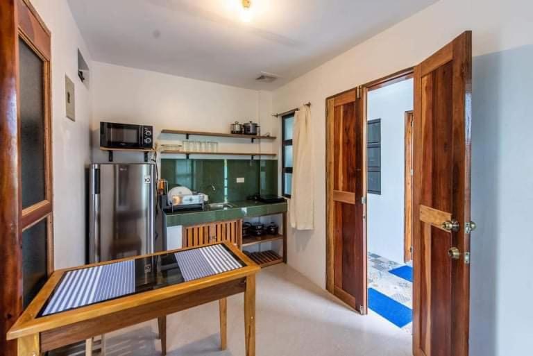 卢纳将军城1-BR flat with kitchen private bath hot and cold shower的厨房配有木桌和冰箱。