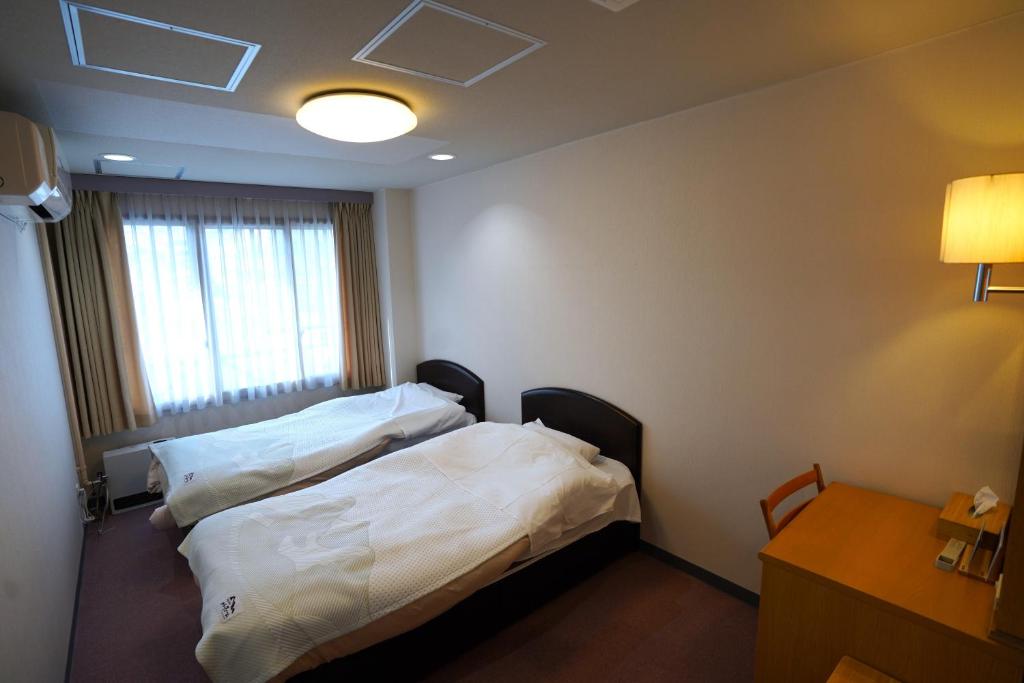 白马村The Hakuba Station Room的酒店客房设有两张床和一张桌子。