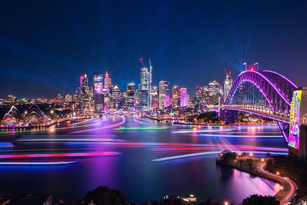悉尼Opera & Harbour bridge view penthouse (3 rooms)的城市天际线的夜晚,有桥和河流