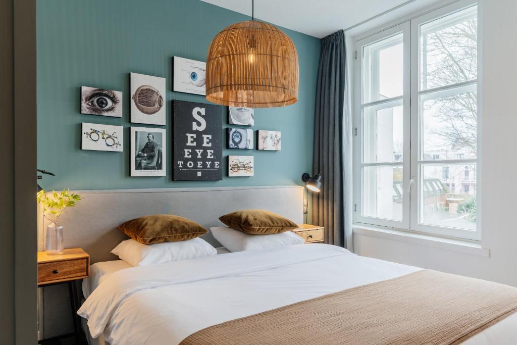 乌得勒支眼睛酒店的一间卧室拥有蓝色的墙壁,配有一张带枕头的床。