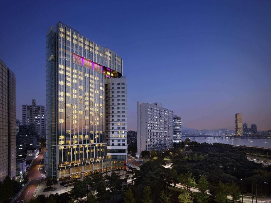 首尔Hotel Naru Seoul MGallery Ambassador的一座高大的建筑,城市里灯火通明