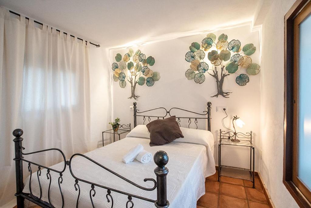 埃斯普霍斯La Pérgola Habitaciones Rústicas的卧室配有一张床,墙上挂着两朵鲜花