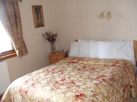 威廉堡奥尔顿塞德宾馆的一间卧室配有一张带花卉床罩的床和窗户。