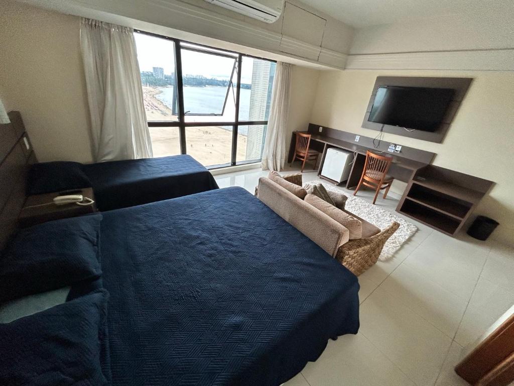 马瑙斯Tropical Executive Flat Vista Incrível para a Orla的一间卧室配有一张床、一张沙发和一台电视。