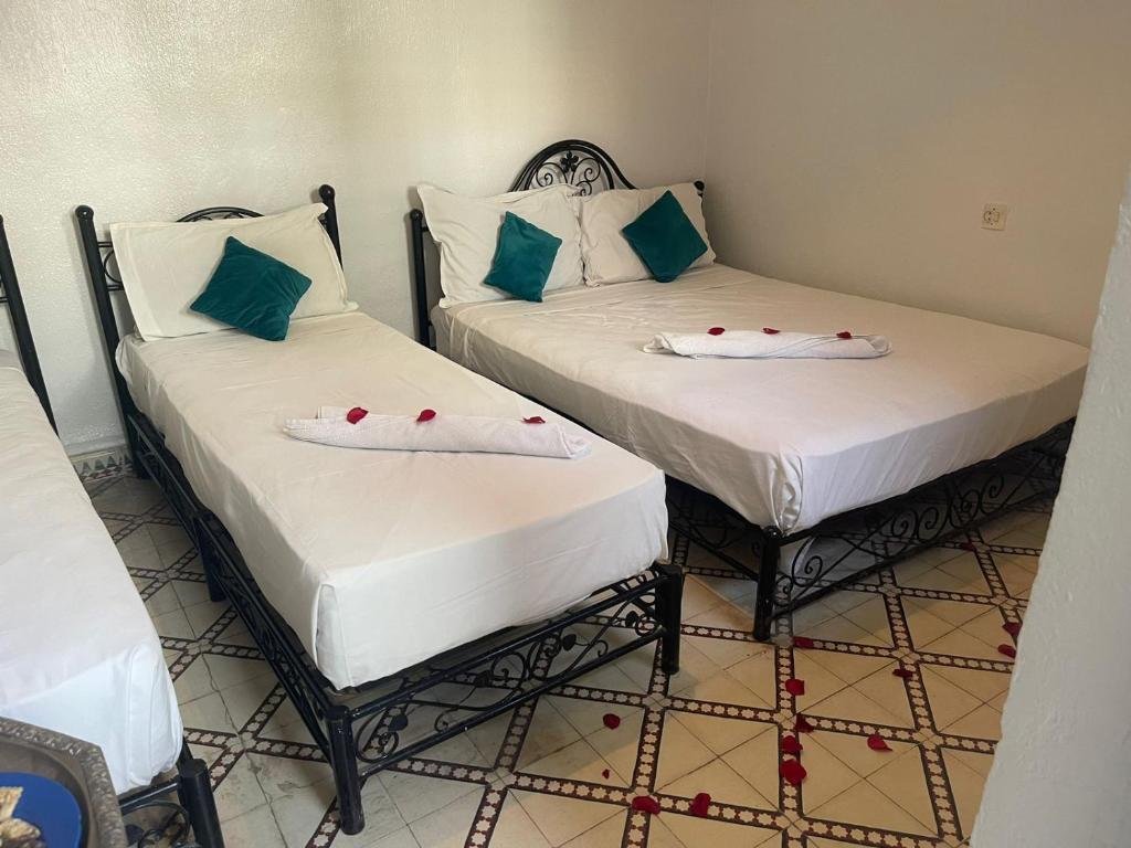 马拉喀什HOTEL EL AMAL的配有两张单人床的客房,玫瑰上摆放着