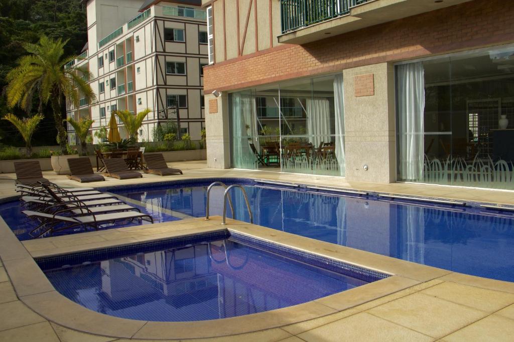 彼得罗波利斯Estúdios no Resort Granja Brasil em Itaipava的一座带椅子的游泳池以及一座建筑