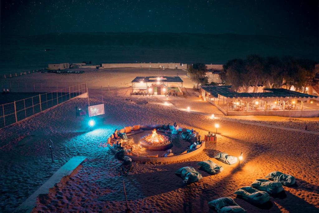 ShāhiqThousand Nights Camp的夜晚享有海滩美景,配有灯光