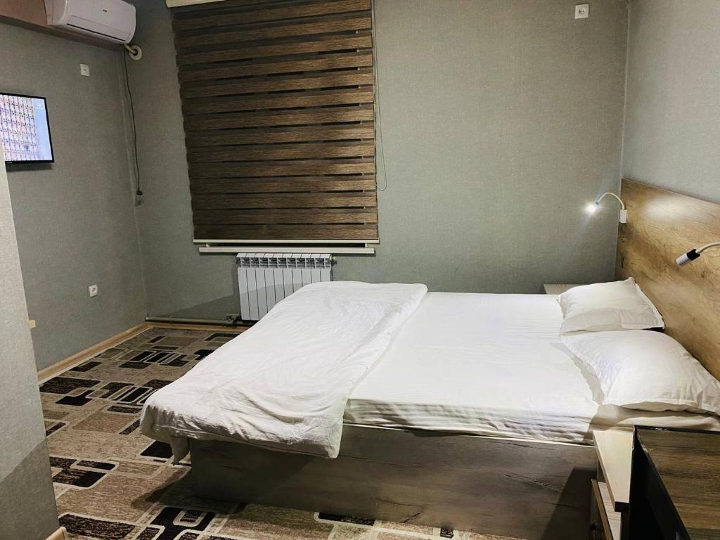 杜尚别ObodHotel的一间卧室配有一张带白色床单的床和一扇窗户。