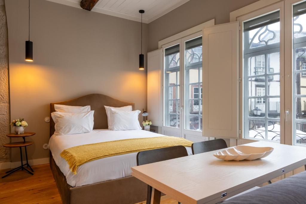 吉马良斯Aparthotel Largo da Oliveira的卧室配有床、桌子和窗户。