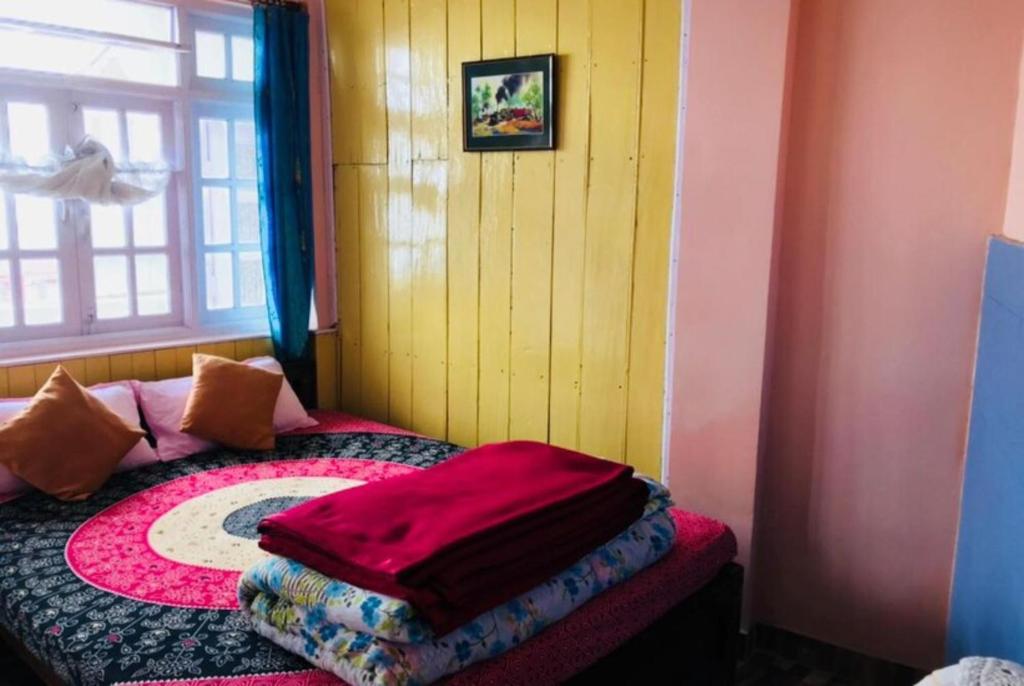大吉岭Hotel New Smriya Homestay Inn Darjeeling的一间卧室配有一张床铺,床上铺有红色毯子