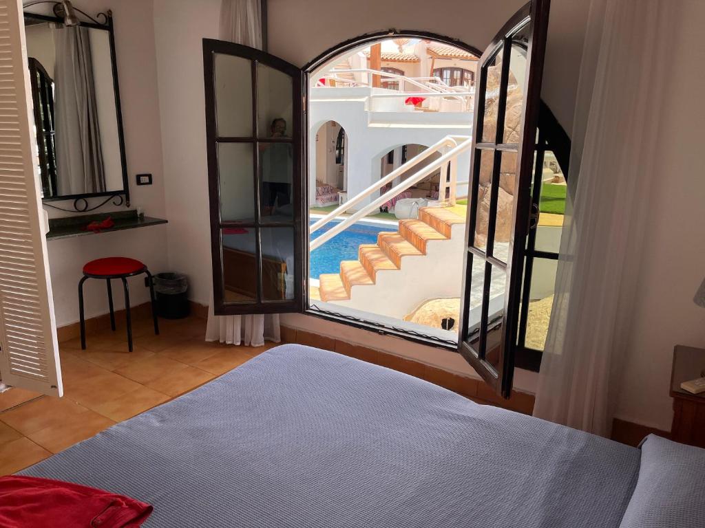 沙姆沙伊赫El Pacha Suites Sharm - Adults Only的一间卧室配有一张床,享有游泳池的景色