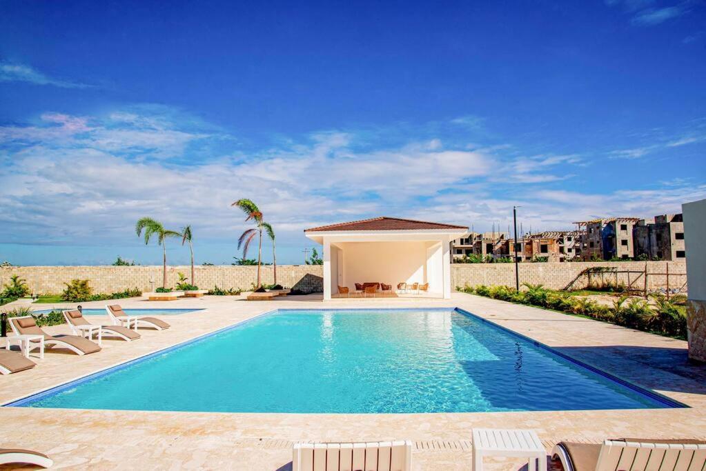 蓬塔卡纳Beautiful Village 3 bedrooms Furnished Pool residencial Velero punta cana的一个带椅子的游泳池和一个凉亭