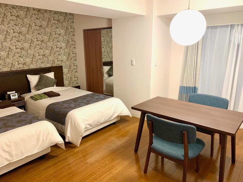 函馆Hotel Global View Hakodate的酒店客房,设有两张床和一张桌子及椅子