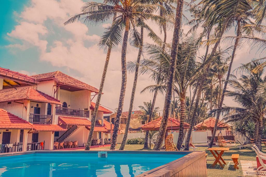 阿杭格默HotelNuvin AHANGAMA的享有棕榈树度假村和游泳池的景色