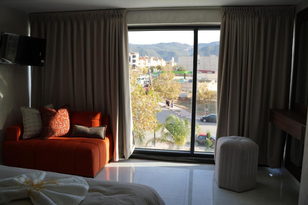 艾兹鲁Le Rocher De L'Atlas的卧室在大窗户前配有橙色沙发